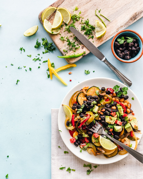 Vegan black bean bowl with avocado, roasted vegetables and fresh lime