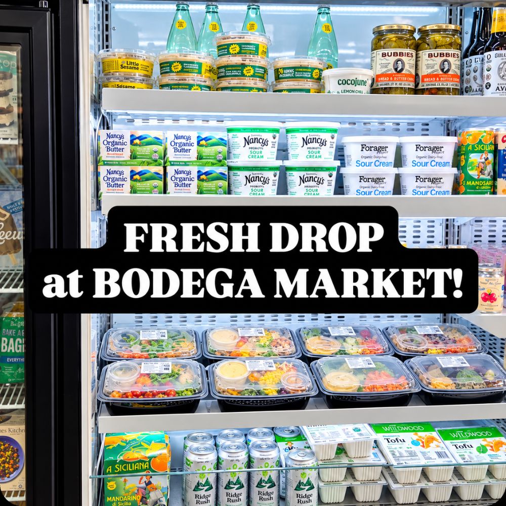 Refrigerated display case stocked with fresh meals, organic dairy products, drinks, tofu, and other groceries, with text reading ‘Fresh Drop at Bodega Market!